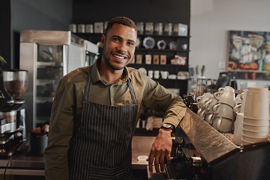 Business Insurance - Portrait of Male Business Owner behind the Counter of a Small Restaurant and Smiling While Looking at the Camera